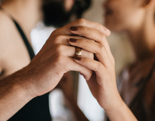 Couple hold hands while lying in bed.