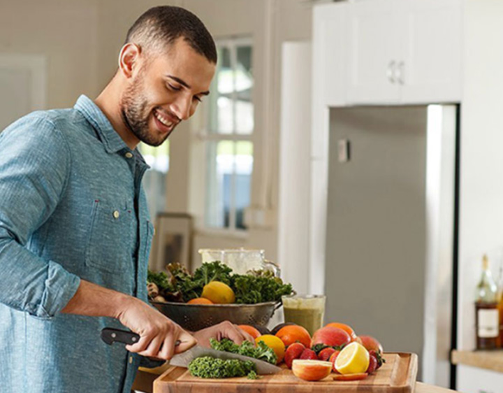 Man in kitchen making salad.