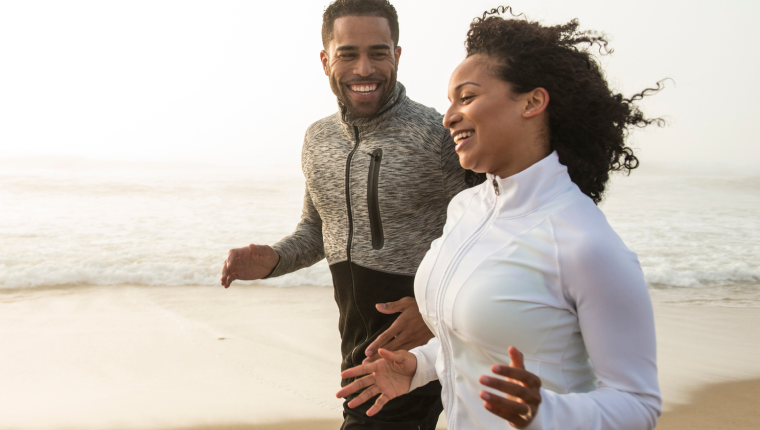 Couple goes for run on beach.