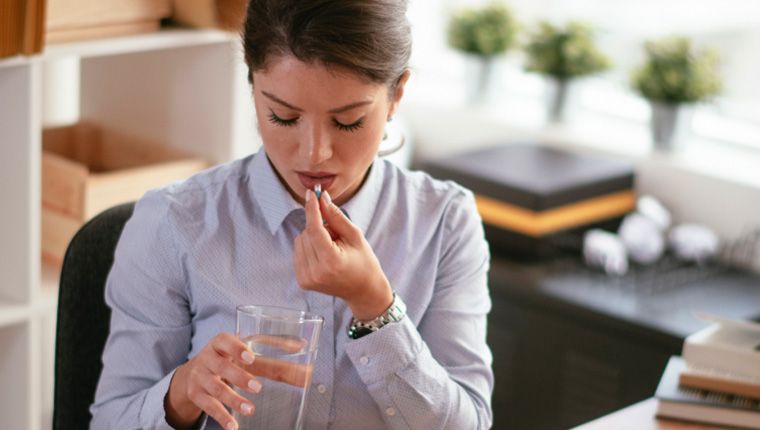 Woman takes vitamin supplement.